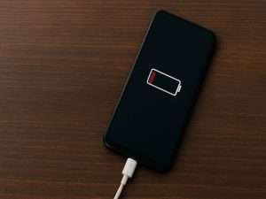 Smartfon podłączony do ładowarki pokazujący ikonę niskiego poziomu baterii